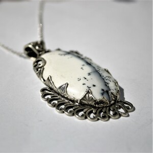 May include: A silver pendant with a white and gray agate stone set in a filigree design.