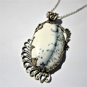 May include: A silver pendant with a white and gray agate stone set in a delicate filigree design.