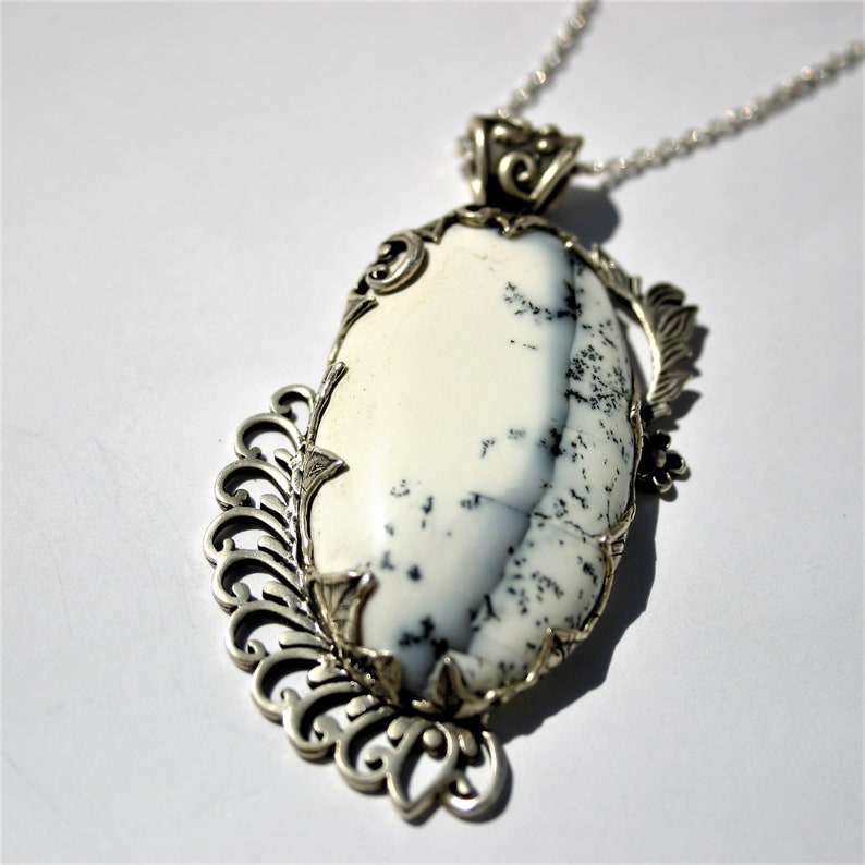 May include: A silver pendant with a white and gray agate stone set in a delicate filigree design.