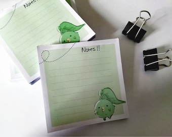 May include: A stack of green and white lined notepad paper with a cartoon character on each page. The character is a green creature with a leaf on its head. The notepad has the text "Notes!!" on the front.