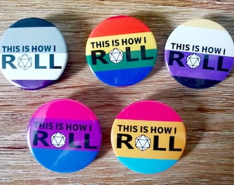May include: Six round buttons with different pride flag colors and a dice graphic. Each button says "This is how I roll".