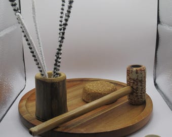 May include: A wooden tray with a pipe, a small cork, and a bamboo container with black and white pipe cleaners.