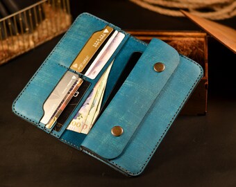 May include: A teal blue leather wallet with multiple card slots and a cash compartment. The wallet is open and has several cards and bills inside.