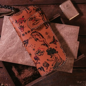 May include: A brown leather wallet with a stitched border and a variety of colorful tattoo-style illustrations, including a mermaid, a bird, a heart, and a diamond. The wallet has the text "新年快乐" and "福" printed on it.