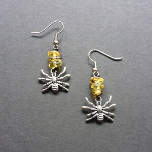 May include: A pair of silver spider earrings with yellow amber beads.