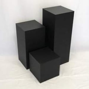 May include: Three black square display risers of varying heights. The smallest riser is 12 inches tall, the middle riser is 18 inches tall, and the largest riser is 24 inches tall.