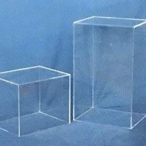 May include: Two clear acrylic display boxes, one larger than the other, on a blue background.