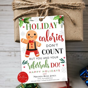 May include: A white gift tag with a gingerbread man illustration and the text "HOLIDAY calories DON'T COUNT BUT YOU AND YOUR referrals DO! HAPPY HOLIDAYS". The tag is decorated with green holly leaves and red berries.
