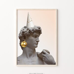 Op de afbeelding: Een witte feestmuts met gouden confetti zit bovenop een grijs marmeren buste van een man. De buste draagt een gouden discobal-oorring.