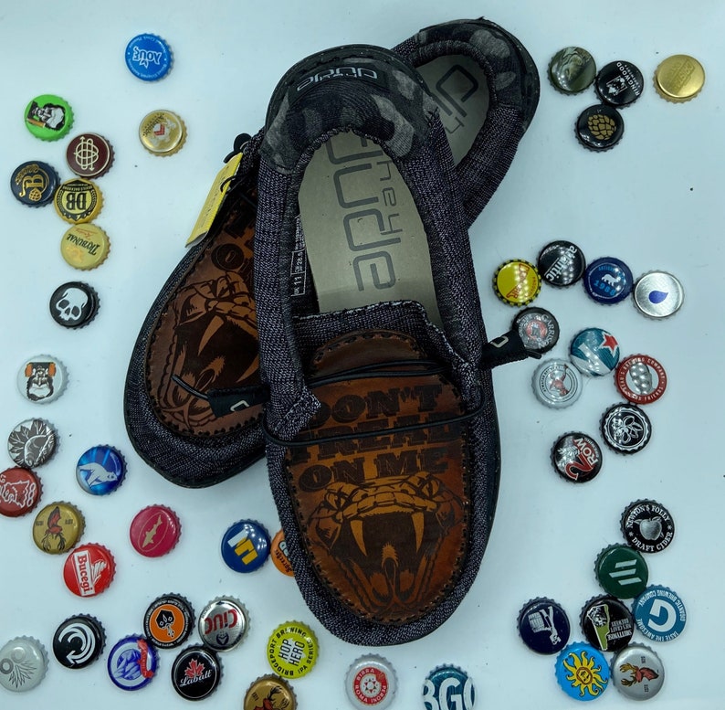 May include: A pair of blue denim shoes with a snake graphic and the text "Don't tread on me".