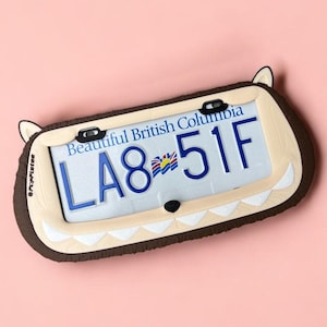 Peut inclure: Plaque d'immatriculation fantaisie de la Colombie-Britannique avec le texte "Beautiful British Columbia" et le numéro de plaque "LA8 51F". La plaque est encadrée dans un cadre marron et beige avec un design de loup de dessin animé.