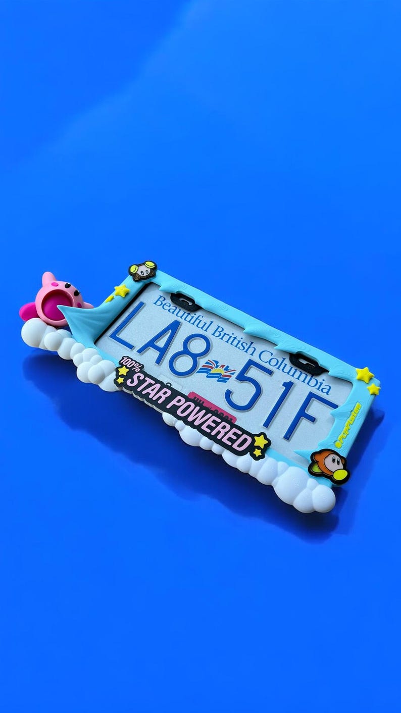 May include: A decorative license plate featuring the text "LA8 51F" and "Beautiful British Columbia". The plate is surrounded by a light blue frame with cartoon characters and the words "STAR POWERED".