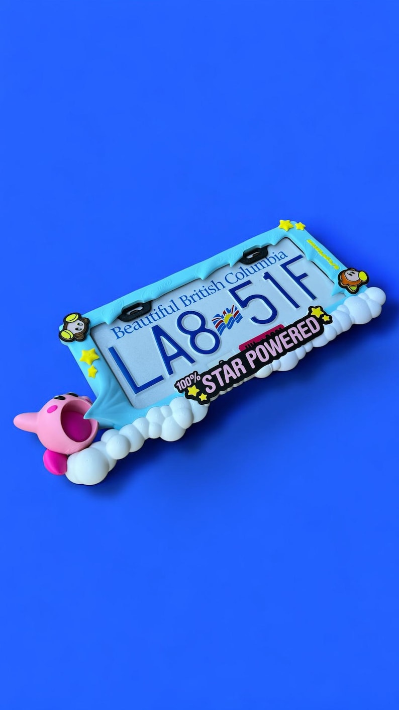 May include: A blue license plate frame with the text "Beautiful British Columbia" and the license plate number "LA8 51F". The frame is decorated with a cartoon character and the words "100% STAR POWERED".