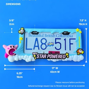 May include: A light blue license plate frame featuring the text "Beautiful British Columbia" and the license plate number "LA8-51F". The frame is decorated with cartoon characters and the words "STAR POWERED". The frame is 17 inches wide and 7.5 inches high.