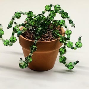 May include: A white ceramic mug with a black handle and the text "But First, Coffee" in a black, bold font. The mug is sitting on a white surface. The mug is approximately 4 inches tall.