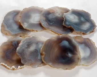 May include: Set of eight agate coasters in shades of brown, gray, and white. Each coaster features a unique natural pattern of swirling agate.