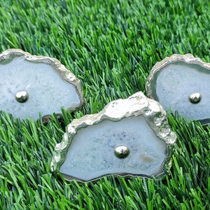 May include: Three white agate knobs with silver metal trim. The knobs are irregularly shaped and have a natural, organic look.