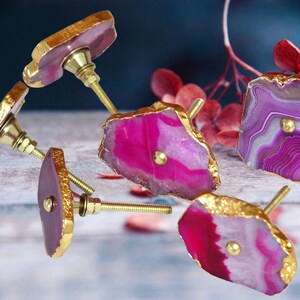 May include: Five agate drawer pulls with gold trim. Each pull features a unique pink and white agate pattern with a gold knob.
