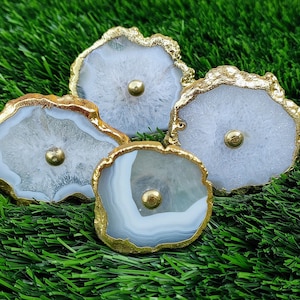 May include: Four white agate drawer pulls with gold trim. The pulls have a natural, organic shape and are perfect for adding a touch of elegance to any home.