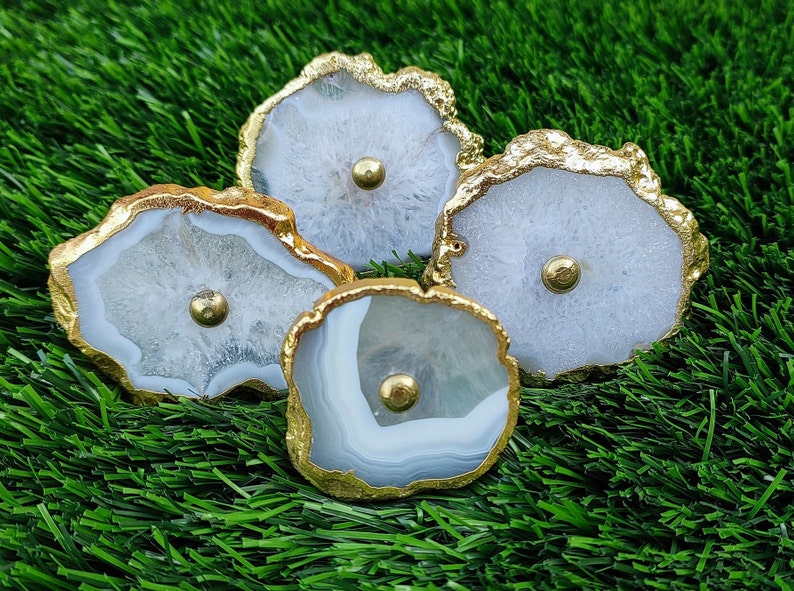 May include: Four white agate drawer pulls with gold trim. The pulls have a natural, organic shape and are perfect for adding a touch of elegance to any home.