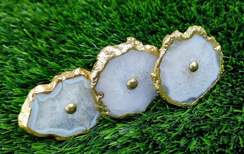 May include: Three white agate drawer pulls with gold trim. Each pull has a round, gold knob in the center.