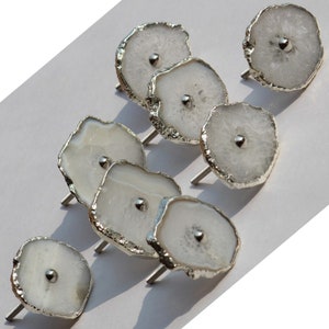 May include: Set of eight white agate drawer pulls with silver metal accents. Each pull features a unique, naturally formed agate slice with a silver metal knob in the center.