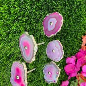 May include: Five pink and purple agate drawer pulls with gold trim. Each pull has a silver knob in the center.