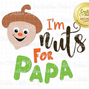 May include: A brown acorn with a smiling face and the text "I'm nuts for Papa" in black and green letters. The text is in a handwritten style.
