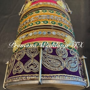 Op de afbeelding: Een traditionele Indiase trommel versierd met kleurrijke armbanden, gouden versieringen en een paarse stoffen basis met zilveren en gouden borduurwerk. De trommel wordt gebruikt bij Indiase bruiloften.