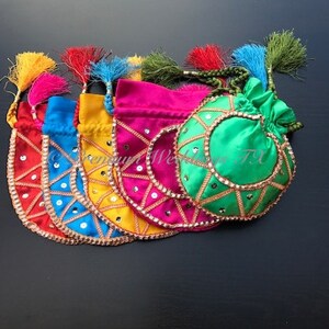 Könnte beinhalten: Fünf bunte Kordelbeutel mit goldenen Verzierungen und Pailletten. Die Beutel sind aus Satin gefertigt und haben Quasten.