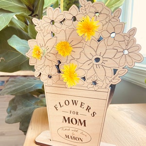 Op de afbeelding: Houten uitsnijding van een vaas met bloemen, met de tekst "Flowers for Mom" en "Picked with love by Mason".