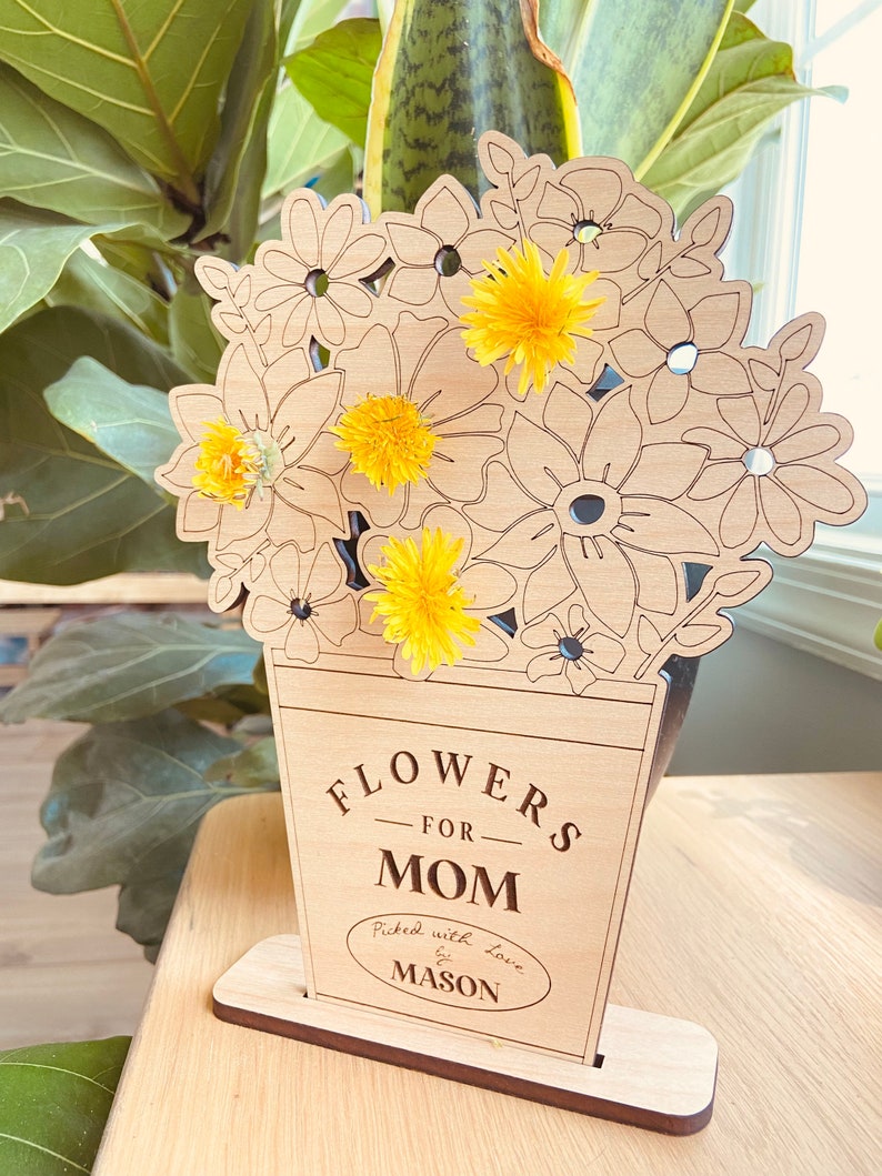 Op de afbeelding: Houten uitsnijding van een vaas met bloemen, met de tekst "Flowers for Mom" en "Picked with love by Mason".