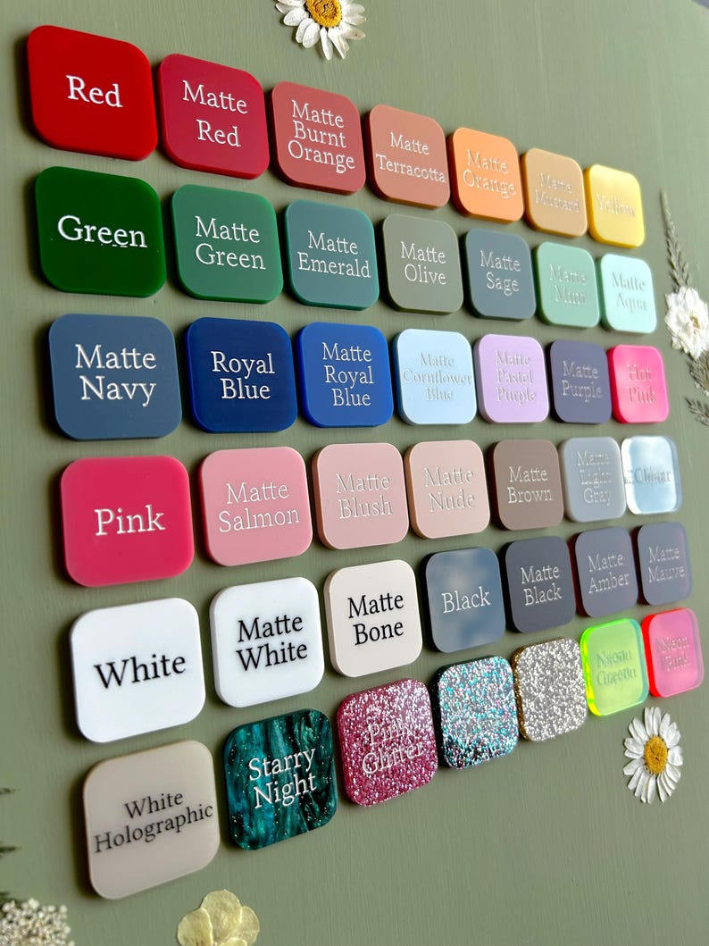 May include: A collection of square acrylic color swatches arranged in a grid, each labeled with its respective color name. The palette includes various shades of red, orange, yellow, green, blue, purple, pink, brown, gray, black, and white, featuring matte, glitter, and holographic finishes.