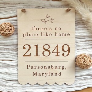 May include: Wooden sign with scalloped edges, featuring the text "there's no place like home" and the address "21849 Parsonsburg, Maryland".