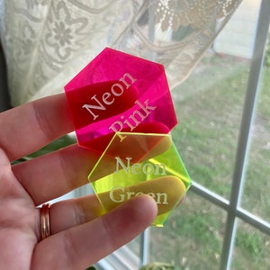May include: Two hexagonal acrylic tags with white text. The top tag is neon pink and says "Neon Pink". The bottom tag is neon green and says "Neon Green".