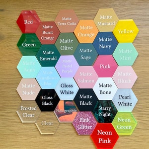 May include: A variety of hexagon-shaped acrylic blanks in different colors and finishes, including matte, gloss, holographic, and neon. The colors include red, green, yellow, blue, pink, purple, orange, white, black, and brown. The finishes are labeled with text.