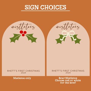 Puede incluir: Dos letreros rosas con la parte superior redondeada, cada uno con el texto "mistletoes" en cursiva. El letrero de la izquierda tiene un mu&eacute;rdago verde con bayas rojas, y el texto "RHETT'S FIRST CHRISTMAS 2024 Mistletoe only". El letrero de la derecha tiene un mu&eacute;rdago verde con un lazo blanco, y el texto "RHETT'S FIRST CHRISTMAS 2024 Bow+Mistletoe Choose red or white for the bow!"