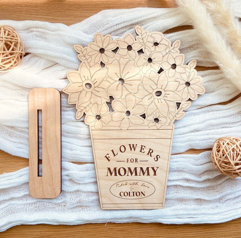 Op de afbeelding: Houten uitsnijding van een boeket bloemen in een pot met de tekst "Flowers for Mommy" en "Picked with love by Colton".