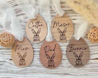 May include: Five wooden Easter egg ornaments with bunny rabbit illustrations and personalized names: Cotton, Mason, Mom, Dad, and Bonnie.