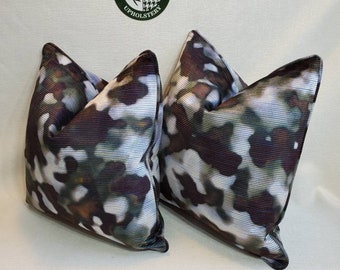 May include: Two decorative throw pillows with a brown, green, and white abstract pattern. The pillows are made of a soft, textured fabric.