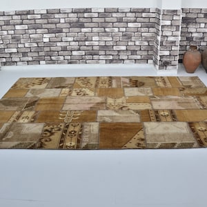 Puede incluir: Una alfombra de patchwork con una variedad de tonos marrones y beige. La alfombra está hecha de diferentes piezas de tela cosidas juntas, creando un diseño único e interesante.