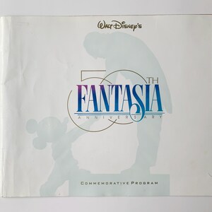 May include: A white commemorative program cover for Walt Disney's 50th Anniversary of Fantasia. The cover features a silhouette of a person and Mickey Mouse, with the words "FANTASIA" in blue and purple, and "50th Anniversary" below.