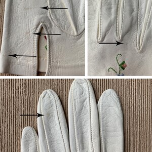 May include: Close-up of off-white leather gloves with delicate floral embroidery. The gloves have a classic design with detailed stitching and a small opening at the wrist. The embroidery features pink and blue flowers with green stems.