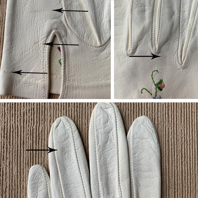 May include: Close-up of off-white leather gloves with delicate floral embroidery. The gloves have a classic design with detailed stitching and a small opening at the wrist. The embroidery features pink and blue flowers with green stems.
