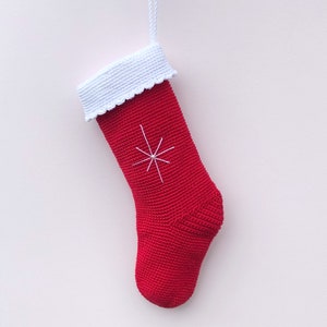 May include: Red crocheted Christmas stocking with a white crocheted cuff and a white snowflake design.