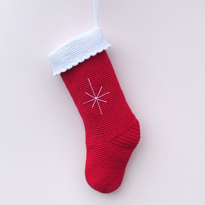 May include: Red crocheted Christmas stocking with a white crocheted cuff and a white snowflake design.