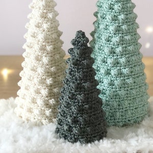 K&ouml;nnte beinhalten: Drei geh&auml;kelte Weihnachtsb&auml;ume in verschiedenen Gr&ouml;&szlig;en und Farben. Der gr&ouml;&szlig;te Baum ist wei&szlig;, der mittlere Baum ist gr&uuml;n und der kleinste Baum ist grau.