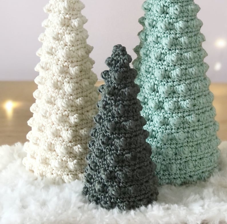K&ouml;nnte beinhalten: Drei geh&auml;kelte Weihnachtsb&auml;ume in verschiedenen Gr&ouml;&szlig;en und Farben. Der gr&ouml;&szlig;te Baum ist wei&szlig;, der mittlere Baum ist gr&uuml;n und der kleinste Baum ist grau.