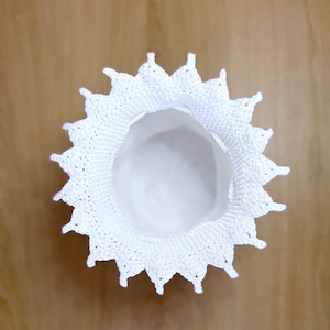 May include: White crocheted doily with a scalloped edge and a center hole.