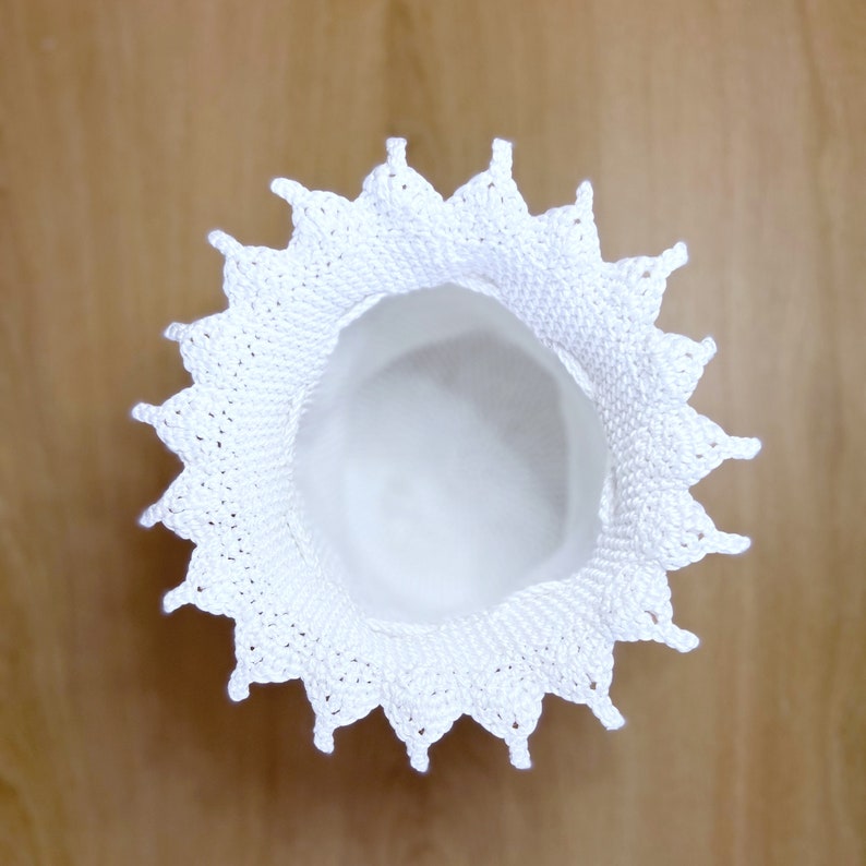 May include: White crocheted doily with a scalloped edge and a center hole.